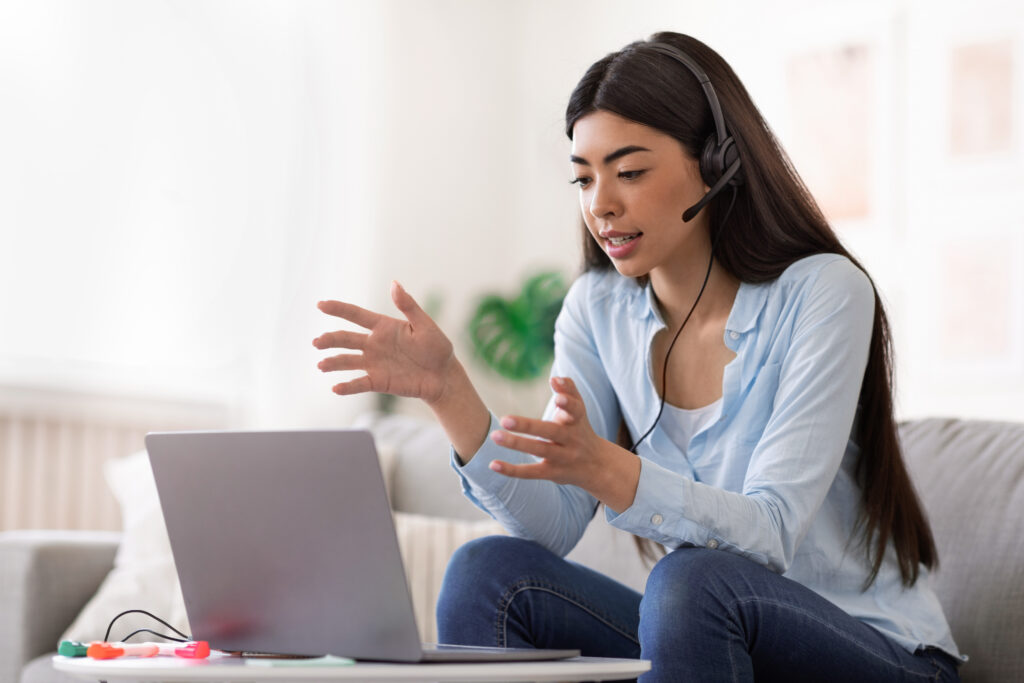 Young adult student in a live online session of ESA-approved dyslexia tutoring with NOW! Programs, wearing a headset and working on a laptop.